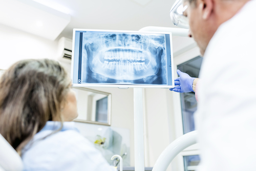 A dentist shows a dental patient an x-ray of their teeth.